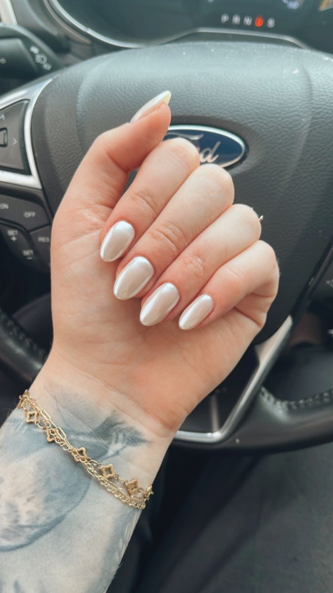 Sophisticated Almond-Shaped Nails with Glossy Pearl Finish Complemented by Gold Jewelry.