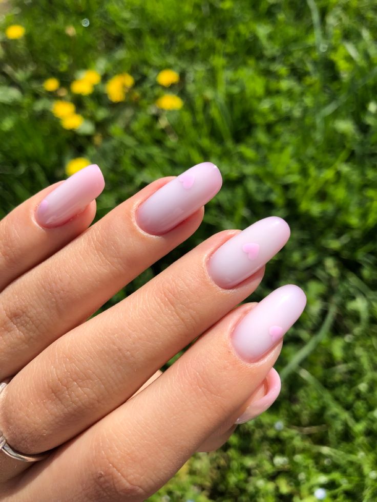 Charming Pastel Pink Gradient Manicure with Playful Heart Accents for a Delicate Spring Look.