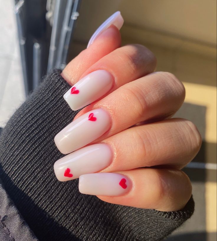 Charming Nail Design: Subtle Nude Base with Tiny Red Heart Accents for Every Occasion