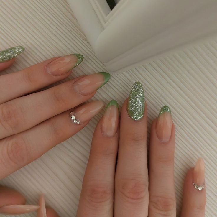 Sophisticated Nude and Green Nail Design with Glitter and Silver Accents.