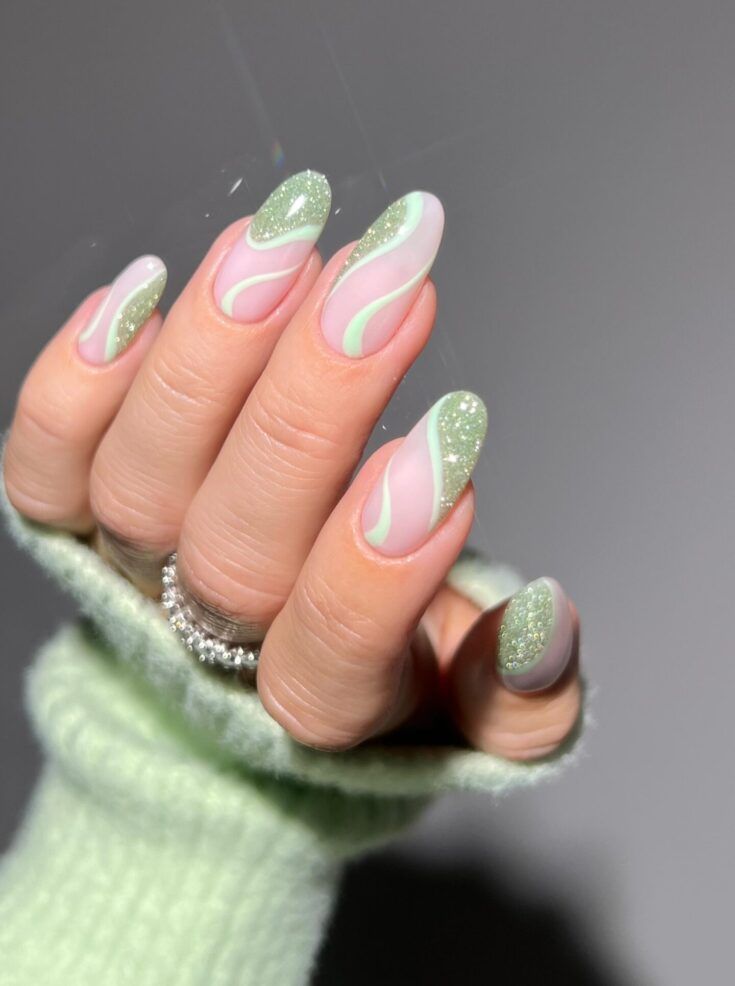 Chic Nail Design with Pale Pink and Soft Green: Glossy Swirls and Glitter Accents for an Elegant Touch.