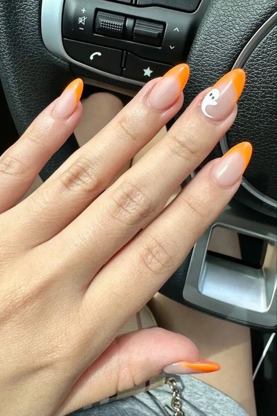 Vibrant Ombre Stiletto Nails with Orange Tips and Whimsical Ghost Accents for Seasonal Elegance.