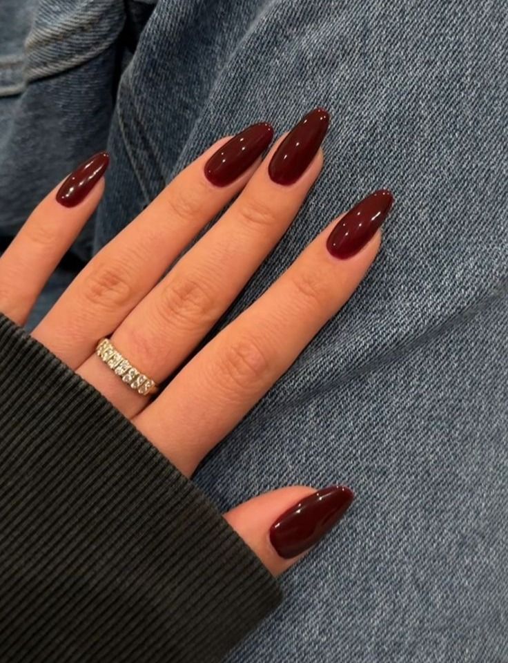 Elegant Glossy Burgundy Almond Nails Shine Against Casual Denim Backdrop