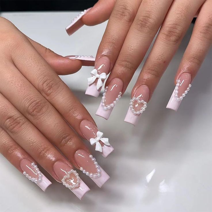 Sophisticated Soft Pink Nails with White Bows and Pearl Accents for Glamorous Occasions.