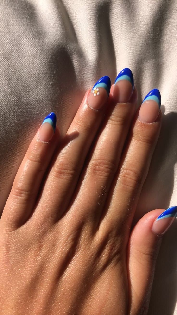 Vibrant Blue Tipped Nails with Whimsical Floral Accent for a Chic Summer Look.