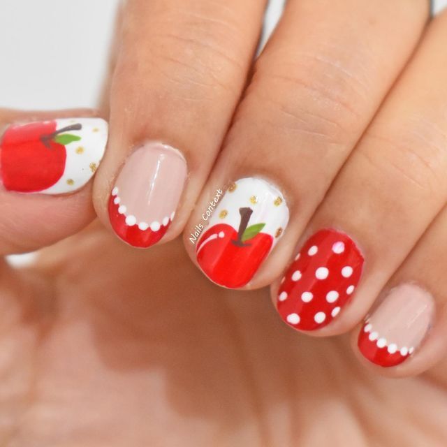 Whimsical Nail Design with Red Apples, Polka Dots, and Glossy Accents.