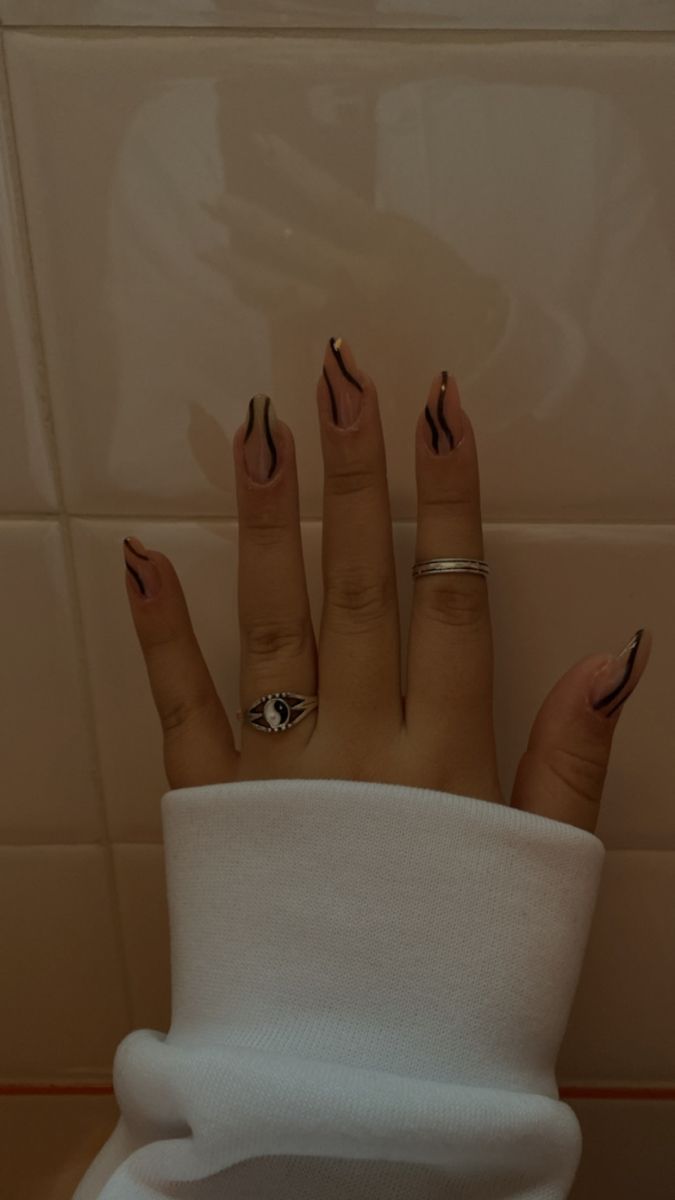 Modern Edgy Nail Design: Nude Base with Striking Black Lines and Sophisticated Rings.