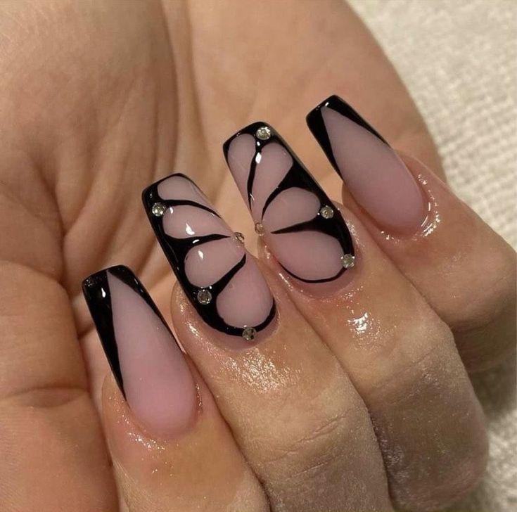 Sophisticated Nail Design: Soft Pink and Bold Black with Unique Patterns and Glamorous Embellishments.