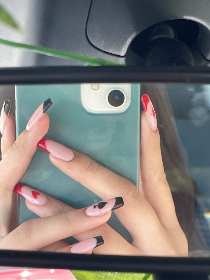 Chic Pink and Black Nail Design with Bold Red Tips and Unique Patterns.