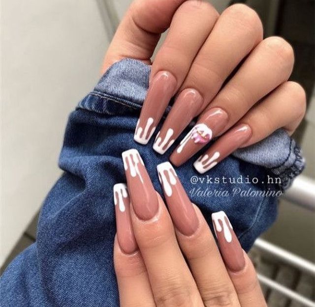 Trendy Almond-Shaped Nails with Nude Base, Elegant White Drips, and Whimsical Accent.