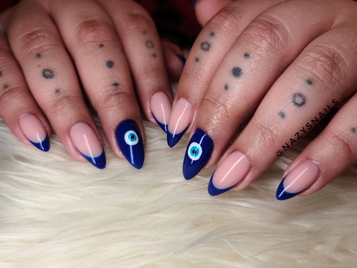 Chic Nude and Navy Nail Design with Bold Blue Eye Accent.