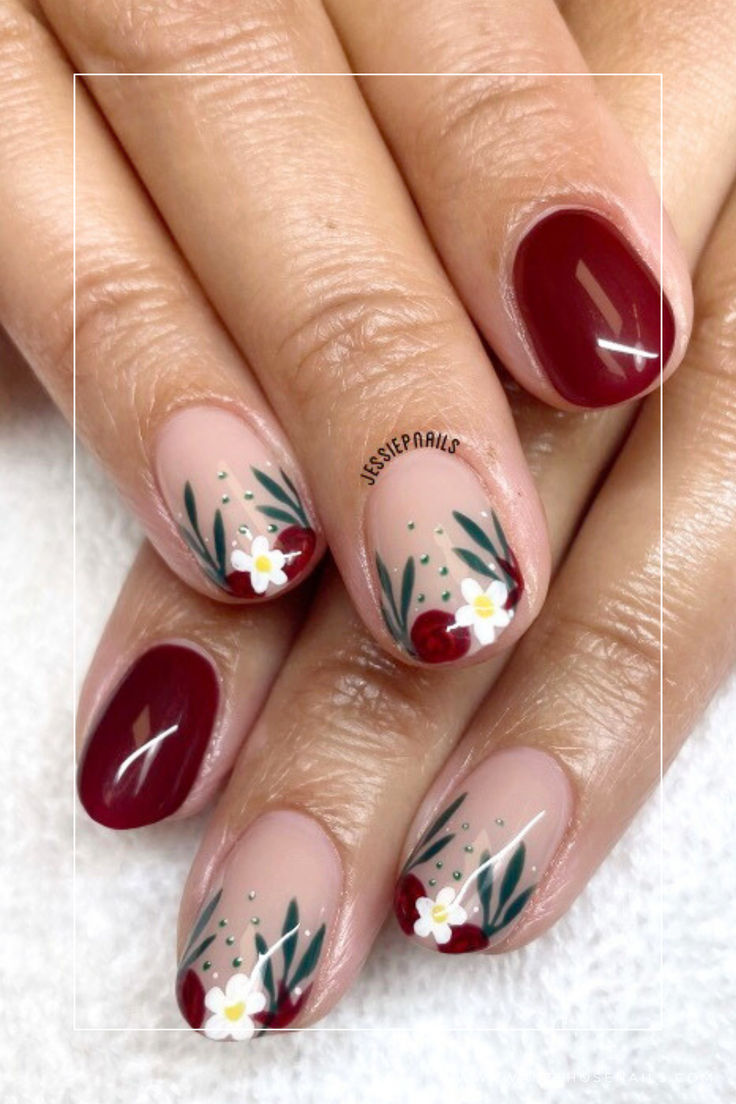 Charming Nail Design: Deep Burgundy and Nude Tones with Floral Accents and Leafy Greens.