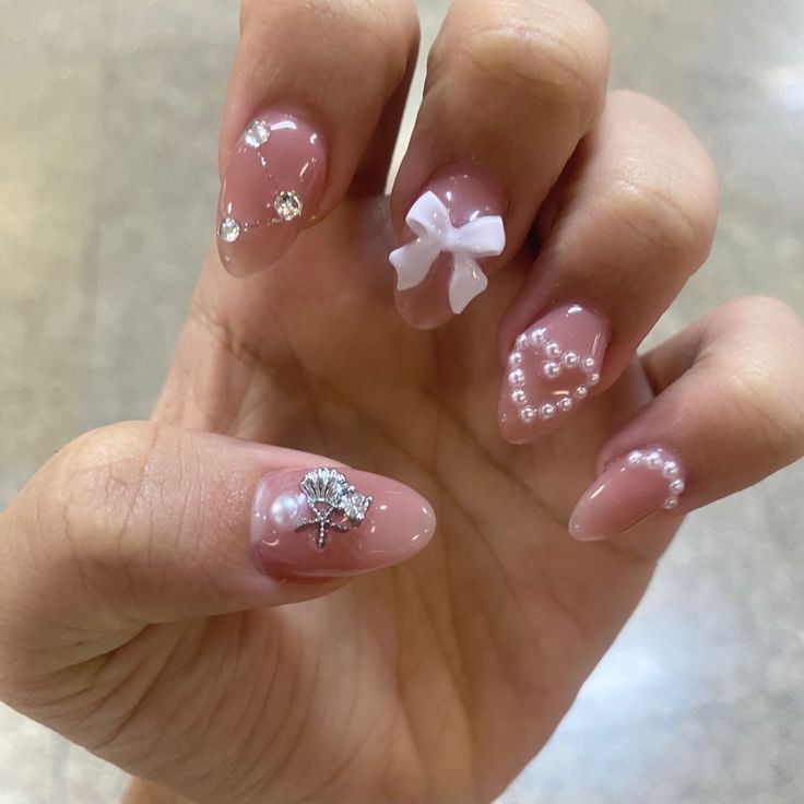 Chic Nail Design: Soft Pink Base with Rhinestones, Cute Bow, and Pearl Accents