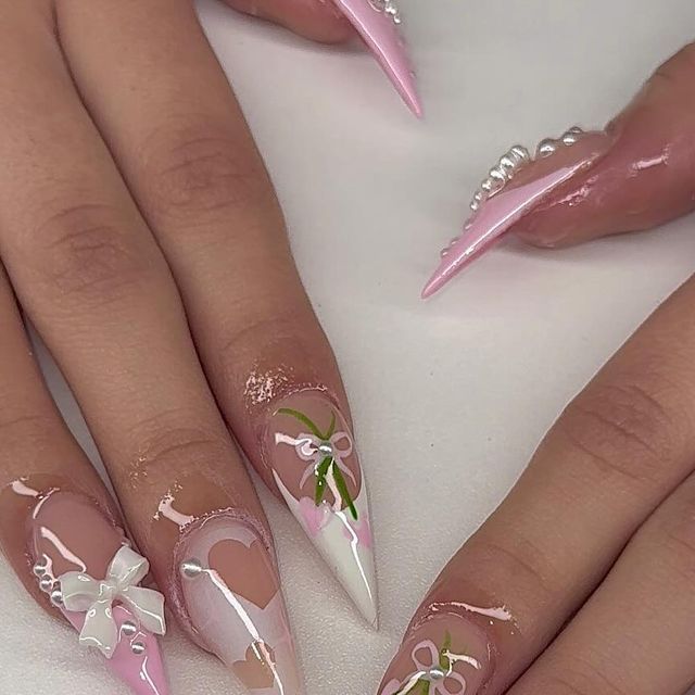 Chic Stiletto Nail Design with Soft Pink and White Accents, Bows, and Floral Motifs.