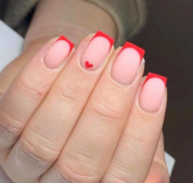 Romantic Nail Design: Soft Pink Base with Bold Red Tips and Heart Accent