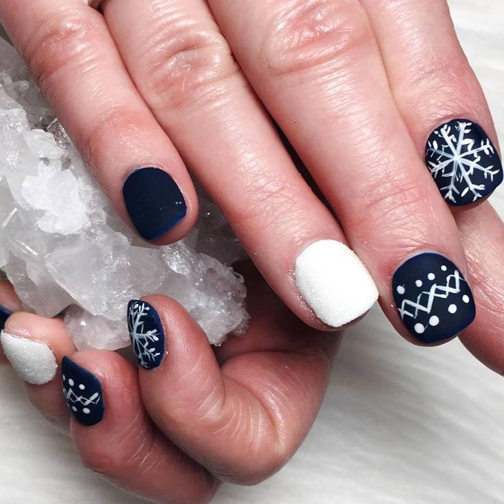 Elegant Winter Nail Design in Deep Navy and Crisp White with Snowflake Patterns and Cozy Knit Motif.