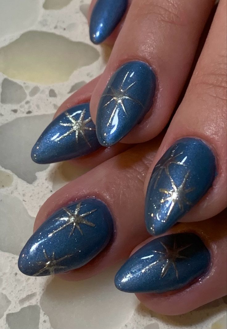 Chic Sparkling Blue Nail Design with Elegant Gold Star Accents for Special Occasions.