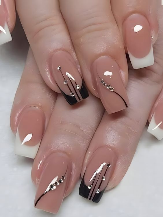 Sophisticated Nude and Black Nail Design with Metallic Accents and a Modern French Twist.