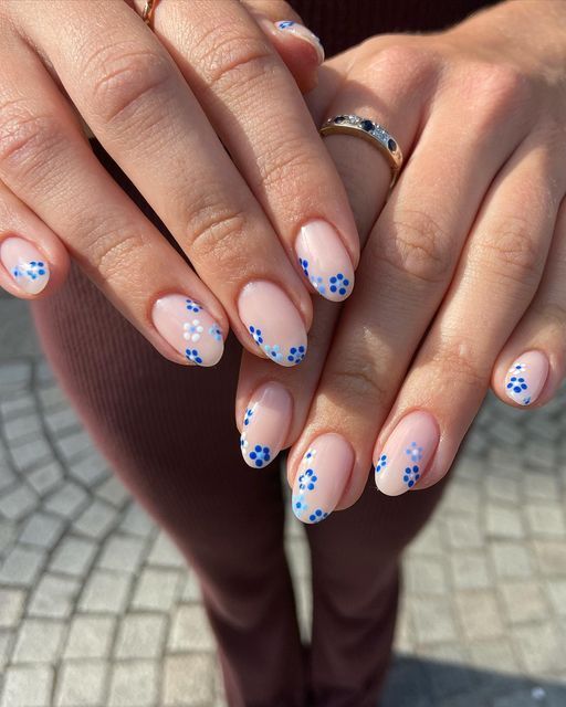 Charming Floral Nail Design: Soft Nude Base with Playful Blue Accents.