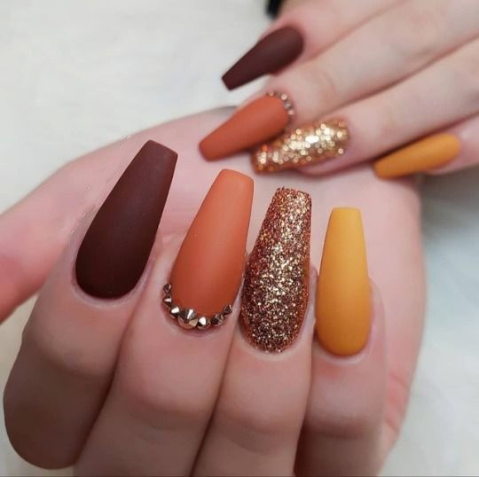 Chic Autumn-Inspired Nail Design with Matte Browns, Rich Oranges, and Glitter Accent.