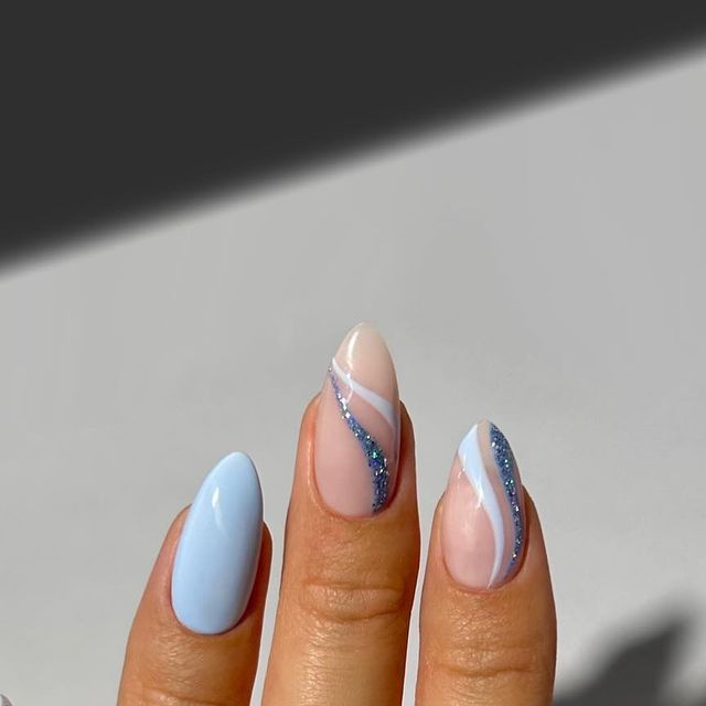 Elegant Nail Design: Soft Blue and Nude with Glitter Accents and Mixed Finishes.