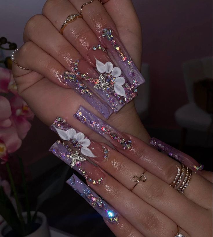 Glamorous Long Acrylic Nails in Soft Lavender with Floral Designs and Rhinestone Accents.