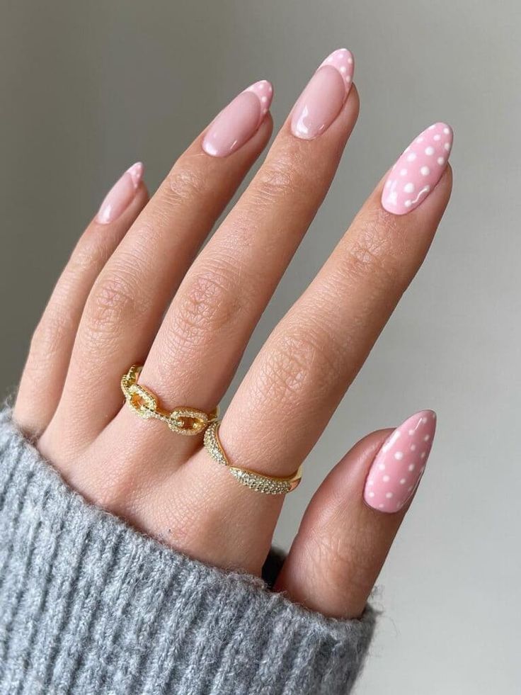 Chic Almond-Shaped Nail Design: Soft Pink with Playful White Polka Dots and Delicate Rings.