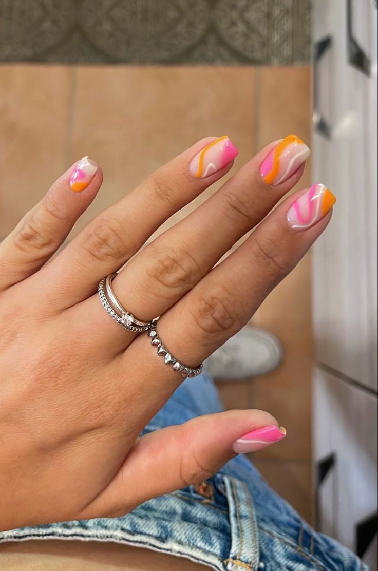 Vibrant Pink, Orange, and White Wavy Nail Design for a Playful Statement.