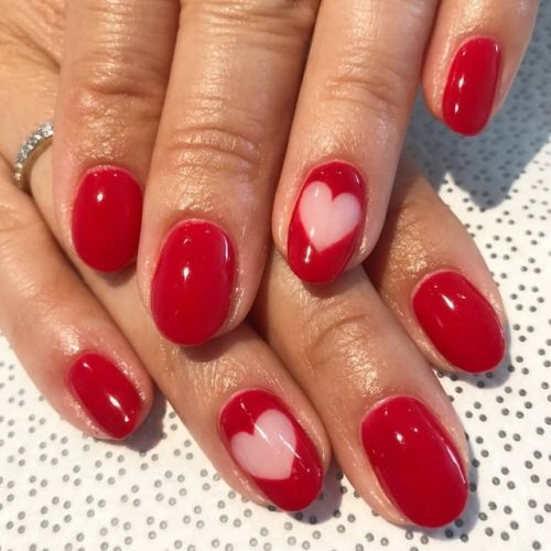 Charming Vibrant Red Nail Design with Delicate Heart Accents for a Romantic Touch.