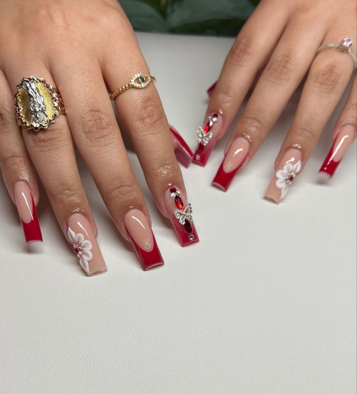 Sophisticated Gradient Nude and Red Nail Design with Floral Patterns and Embellishments