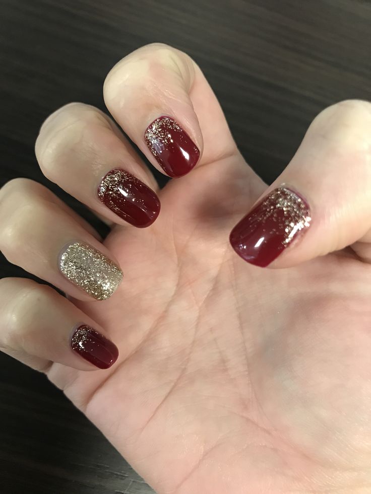 Glamorous Deep Burgundy Nail Design with Shimmering Gold Glitter Accents.