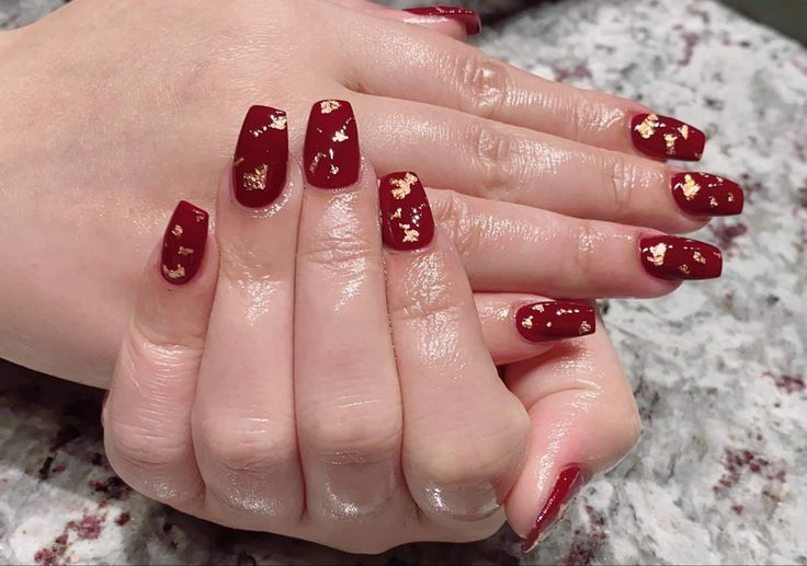 Sophisticated Red Nails Enhanced with Gold Leaf Accents for a Glamorous Touch.