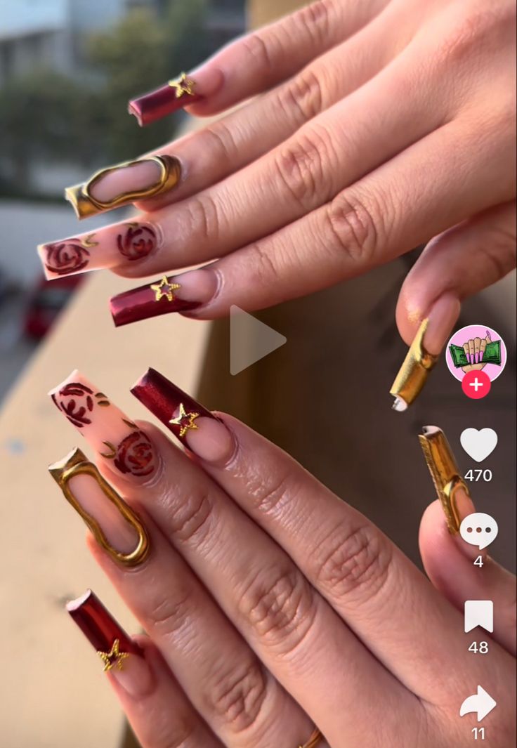 Elegant Deep Red and Metallic Gold Nail Design with Intricate Roses and Whimsical Star Accents.