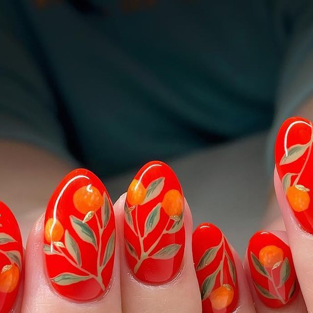 Whimsical Nail Art: Vibrant Red Nails Adorned with Playful Orange Fruits and Elegant Green Leaves.