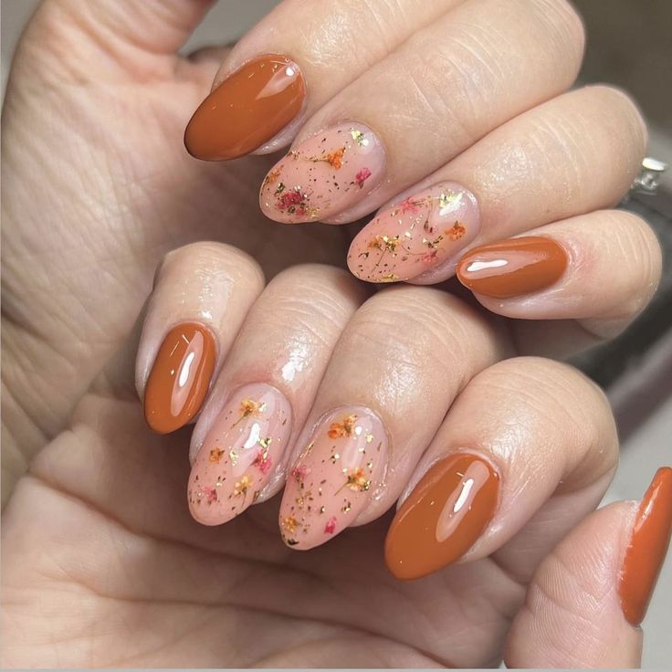 Sophisticated Autumn-Inspired Almond-Shaped Nail Design with Warm Orange Base and Glitter Accents.