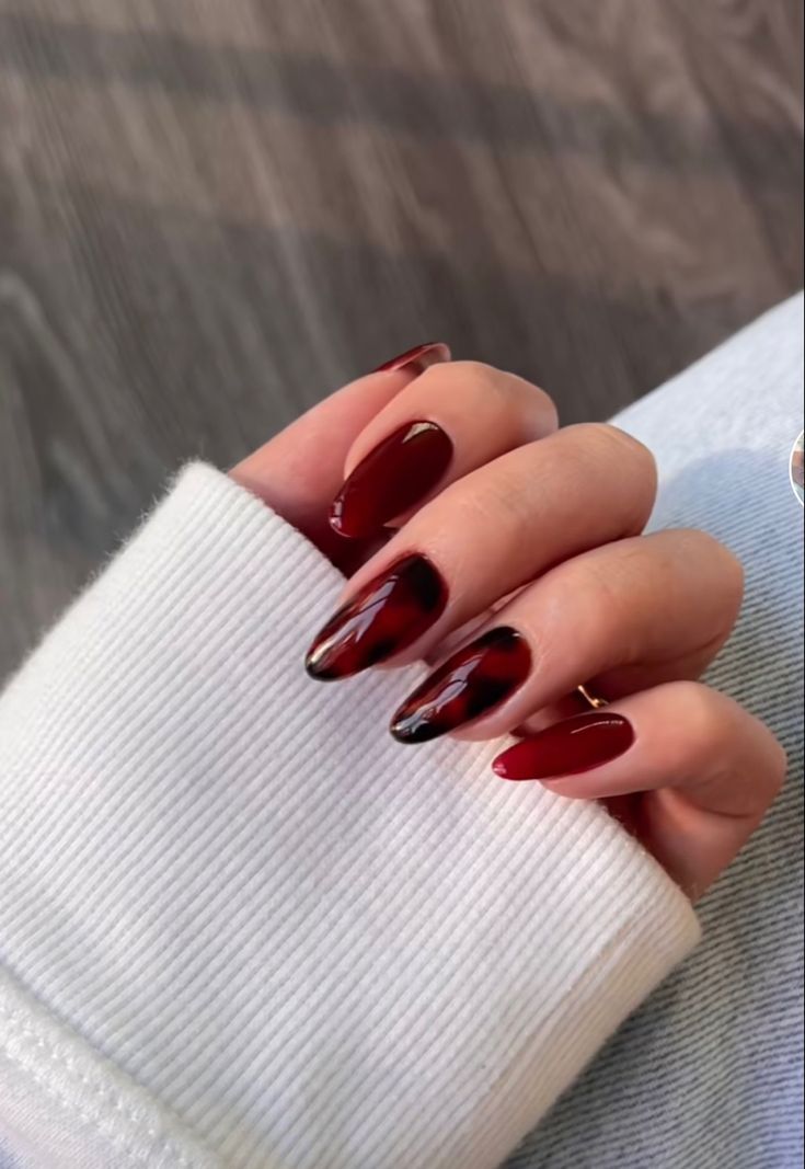 Elegant Almond-Shaped Burgundy Nails with Glossy Finish and Bold Black Geometric Accents.