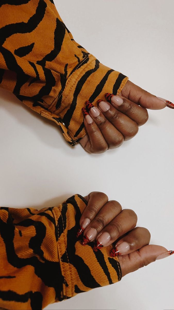 Chic Nude and Bold Red Nail Design Paired with Trendy Tiger-Striped Sleeve.