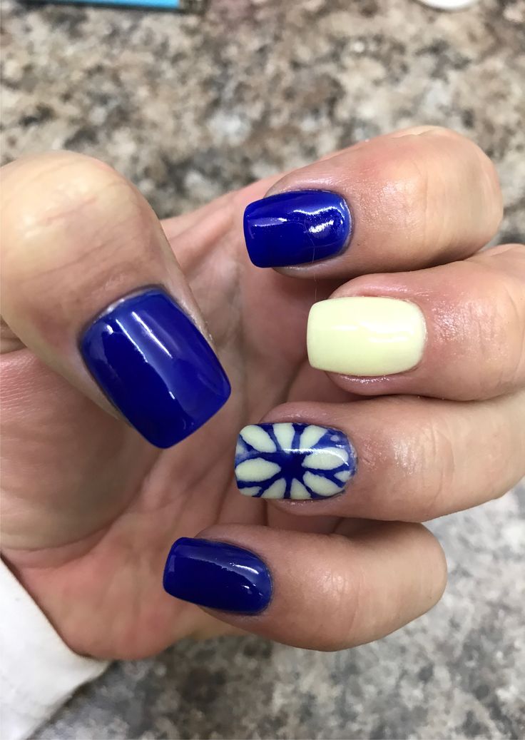 Vibrant Deep Blue and Soft Yellow Nail Design with Elegant White Accent Patterns.