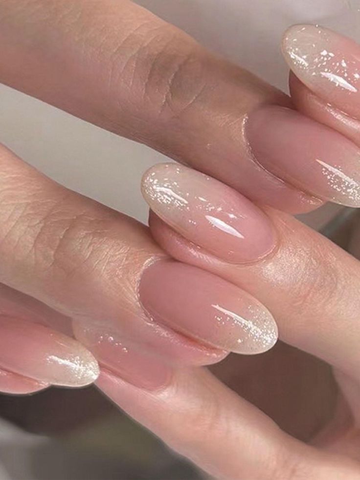 Elegant Soft Ombre Nail Design: Sheer Nude Base to Glittering White Tips with Subtle Shimmer.