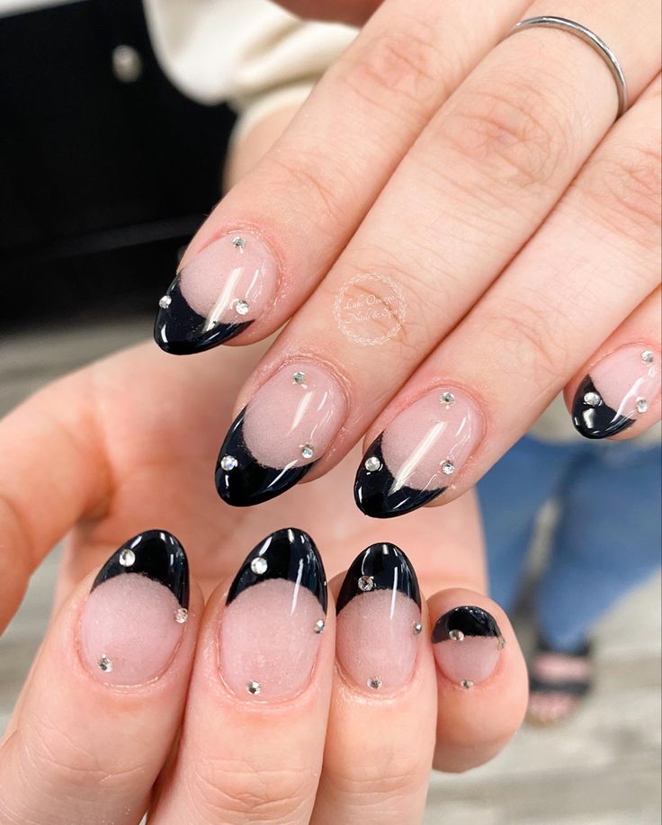 Chic Black French Tip Nails with Glossy Nude Base and Glamorous Rhinestone Accents.