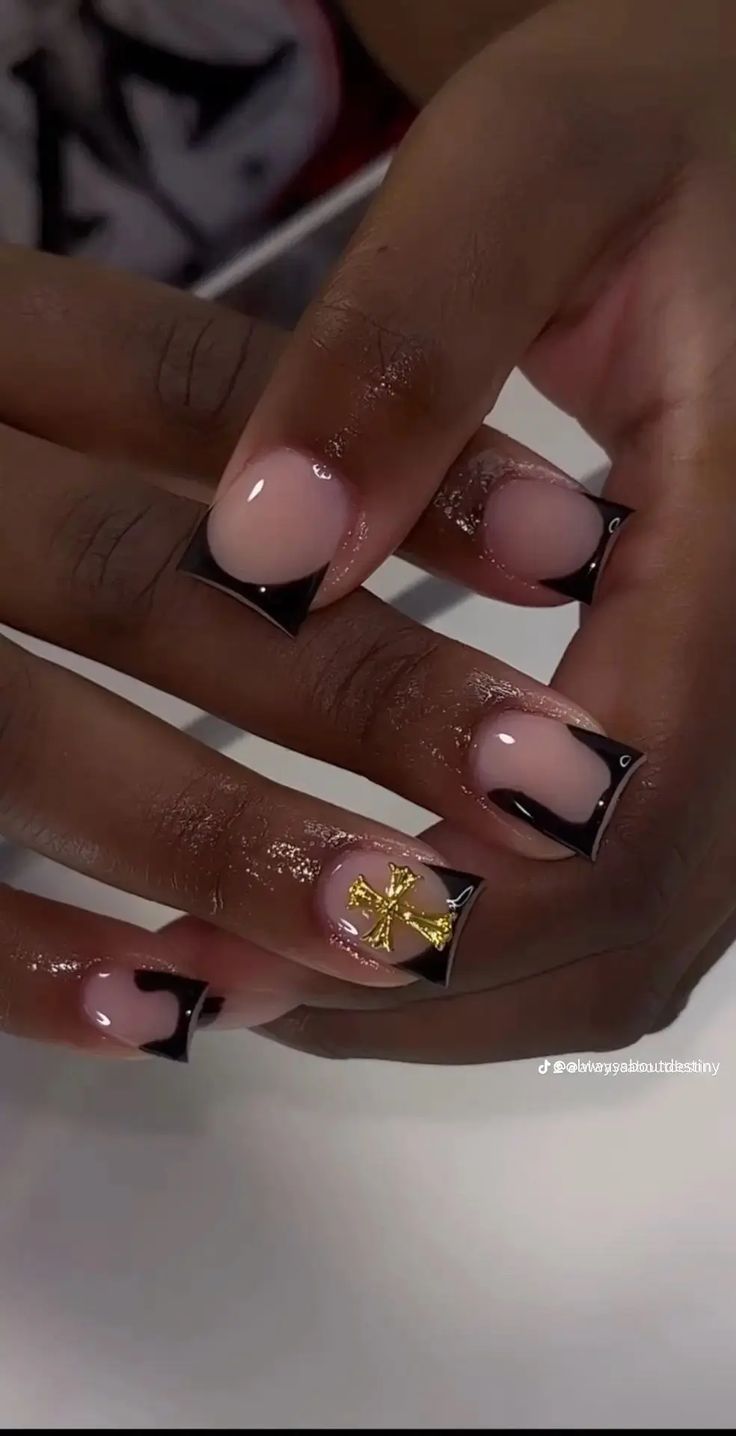 Sophisticated Modern French Tip Nail Design with Glossy Nude Base, Striking Black Tips, and Gold Cross Accent.