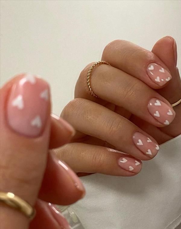 Charming Nail Design: Soft Pink Base with Playful White Heart Accents