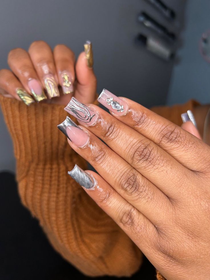 Striking Metallic and Nude Nail Design with Elegant Patterns and Textures.