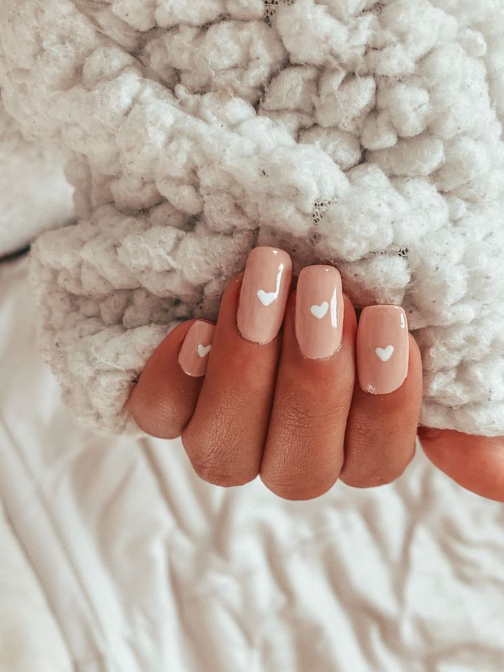 Charming Nude Nail Design with Delicate White Heart Accents for a Cozy, Romantic Flair.