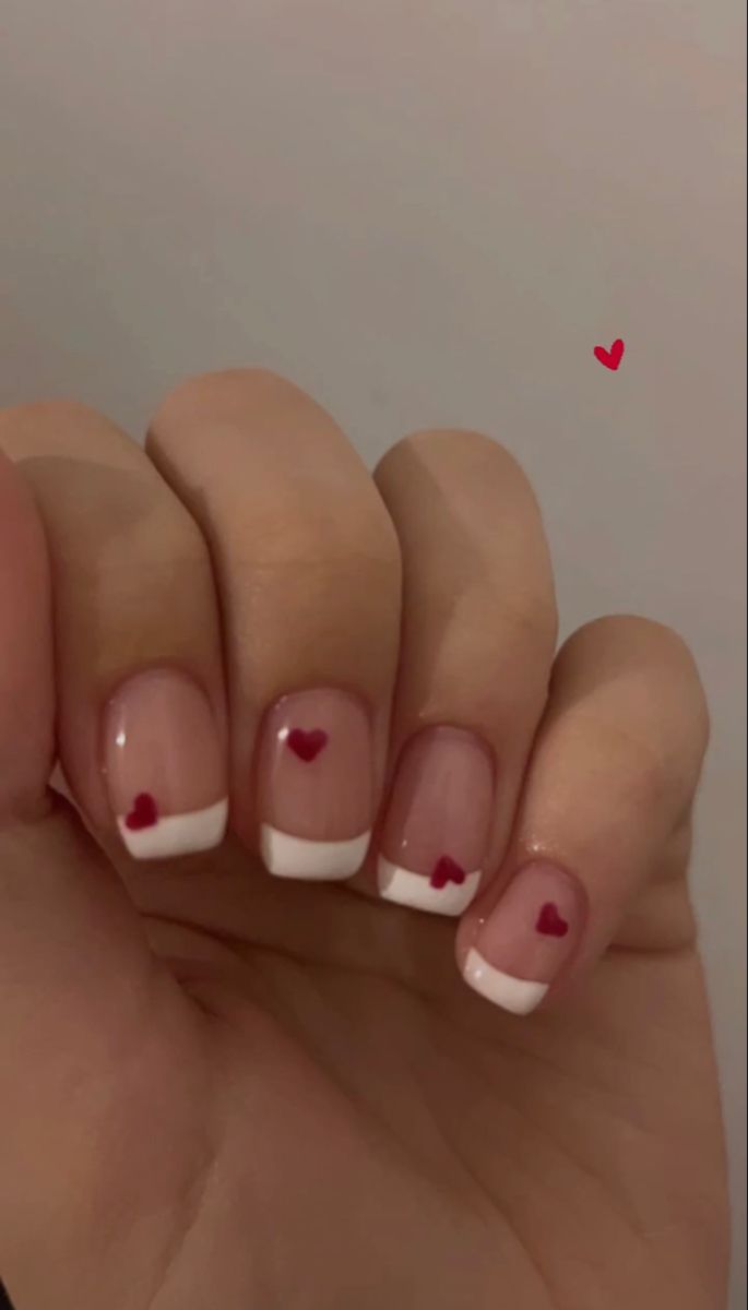 Charming French Tip Nail Design with Playful Red Hearts: A Perfect Blend of Elegance and Fun.