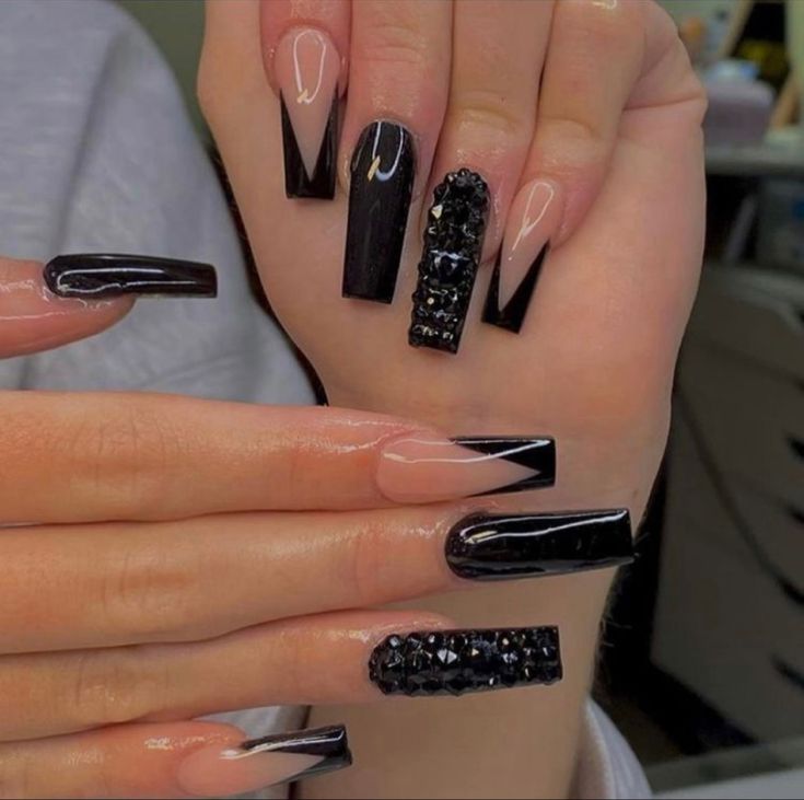 Chic Edgy Nail Design: Glossy Black and Nude Accents with Geometric Shapes and Gemstone Detailing.