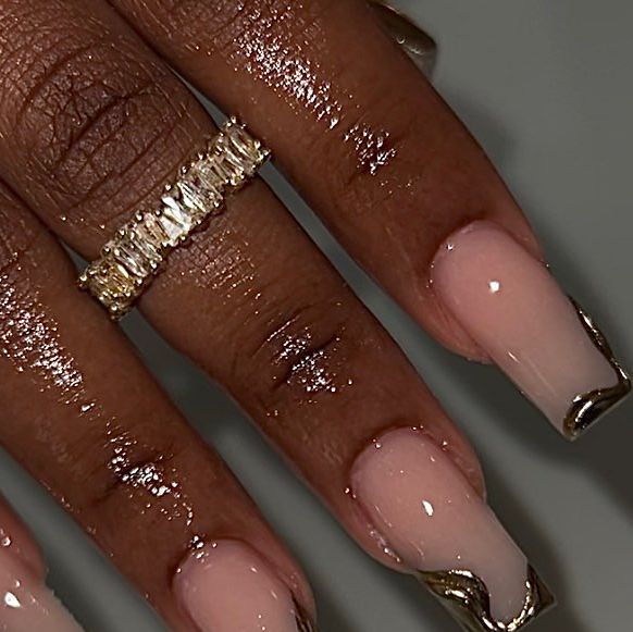 Chic Nude Nail Design with Gold French Tips and Statement Ring for a Modern Glamorous Look