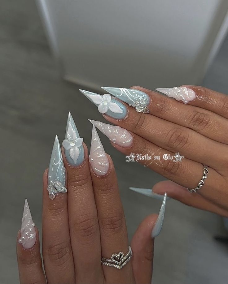 Whimsical Pastel Blue and Pink Floral Stiletto Nails with Shimmering Embellishments.