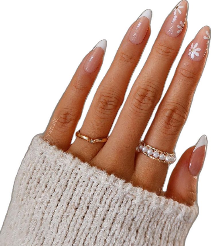 Chic Nude and White French Manicure with Floral Accents and Elegant Rings.