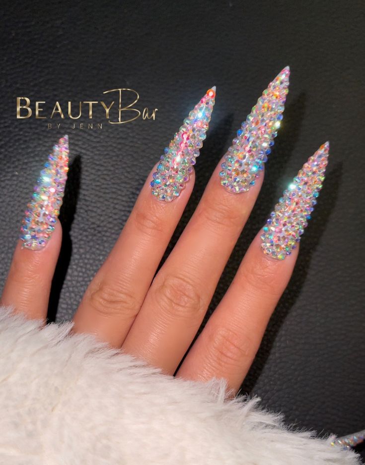 Dazzling Stiletto Nails Adorned with Shimmering Crystal Rhinestones for a Bold Statement.